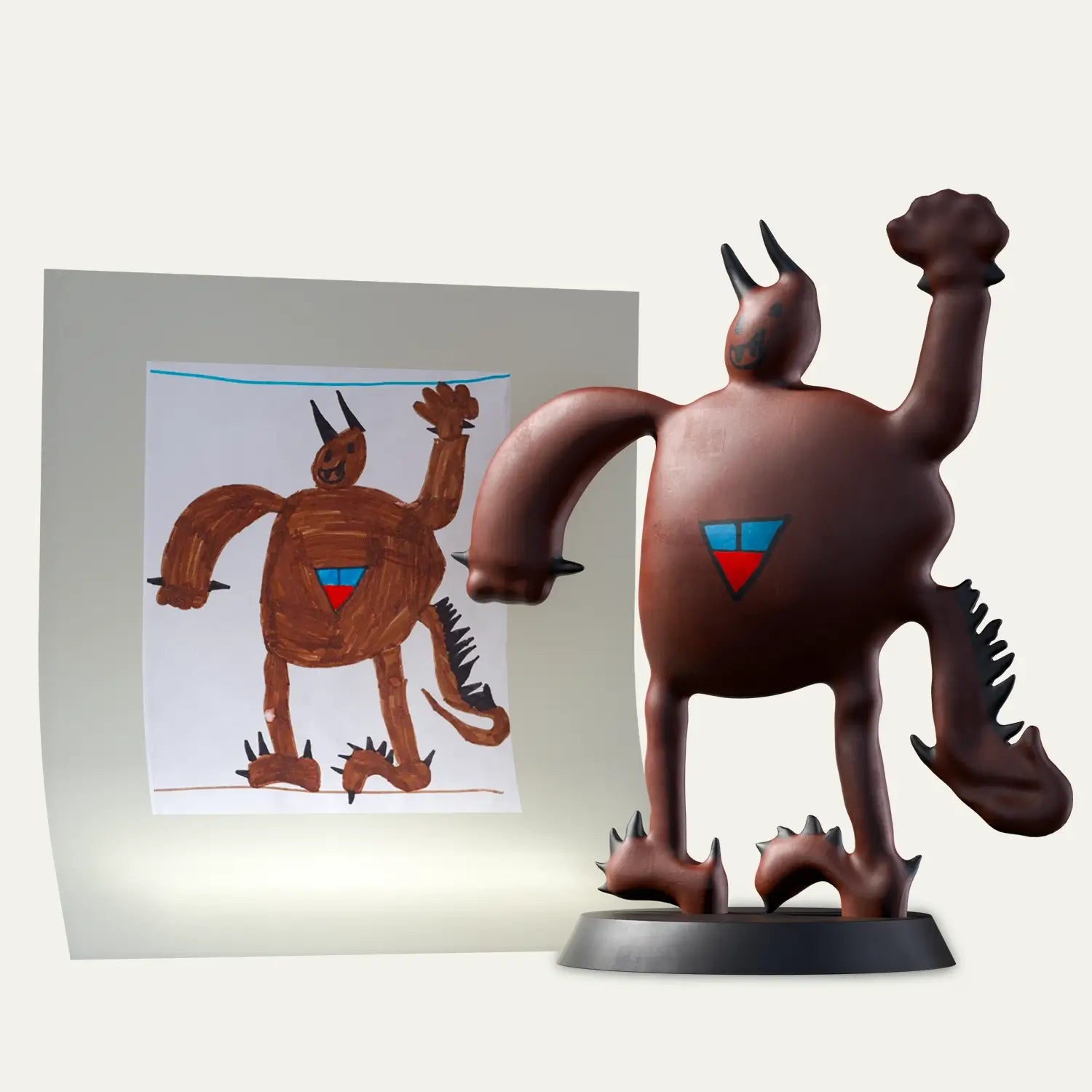 A strong, spiky brown monster drawn by a child is recreated as a 3D figurine, side by side with the original artwork for a memorable gift with audio memory.