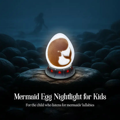 OstanesKids mermaid egg nightlight glowing on a rocky shore, with red gem base and a distant silhouette of a mermaid.